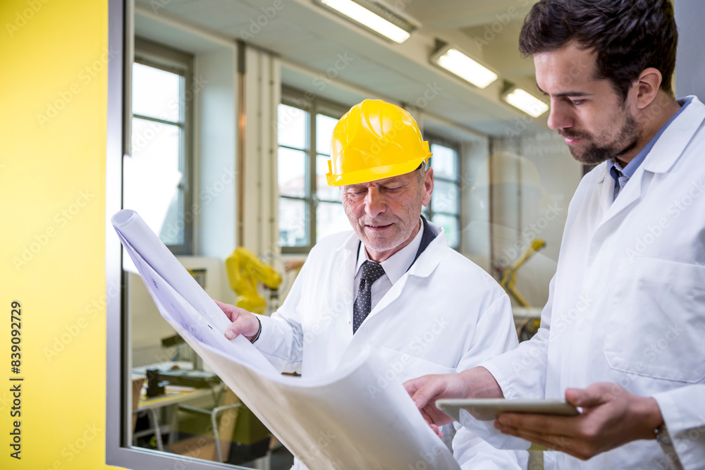 Two engineers in factory looking at plan Two engineers in factory looking at plan