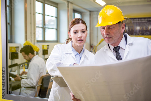 Two engineers in factory looking at plan photo