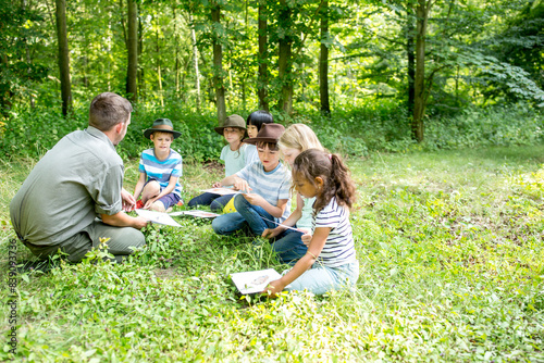 Papier peint School children learning to distinguish animal species in forest