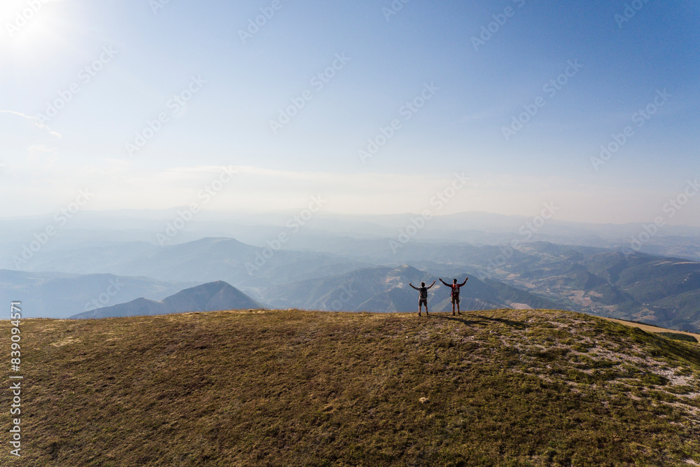 Italy, Monte Nerone, two hikers on top of a mountain enjoying the view Italy, Monte Nerone, two hikers on top of a mountain enjoying the view