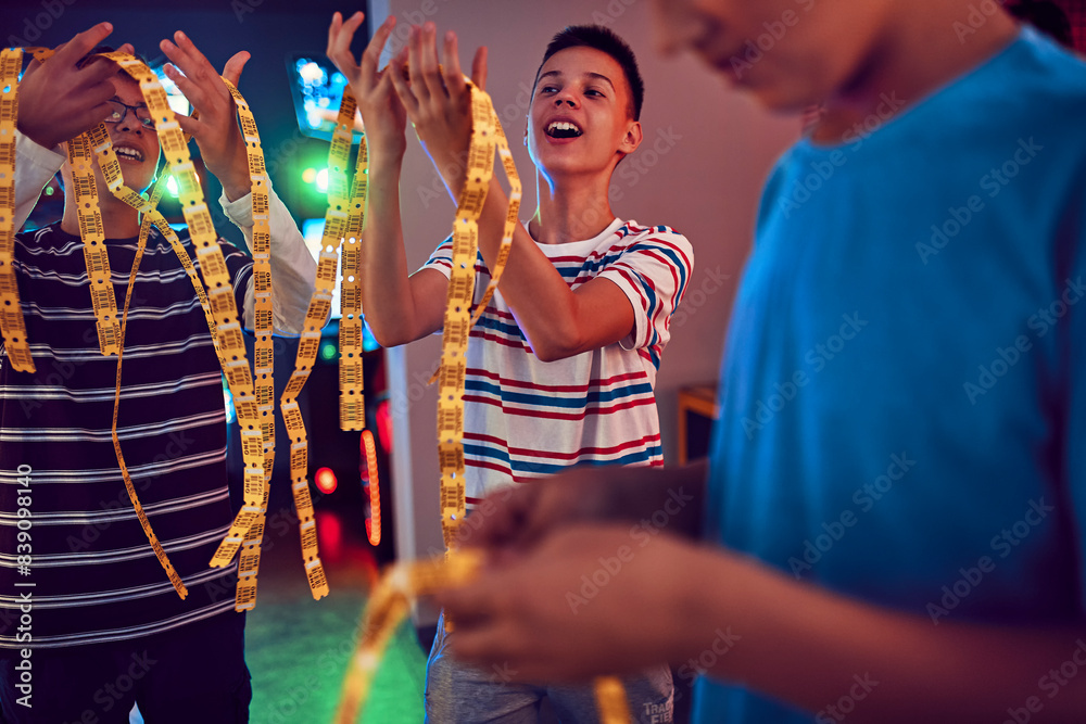 Teenage friends having fun with tickets in an amusement arcade