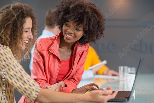 Two happy women in office sharing laptop