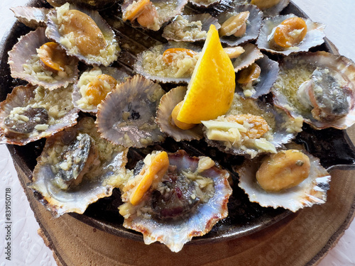 Azores cuisine -Lapas, a mollusk similar to clams, also known as limpets,prepared in a griddle pan, cooked simply in a sauce of butter, garlic, and lemon juice photo