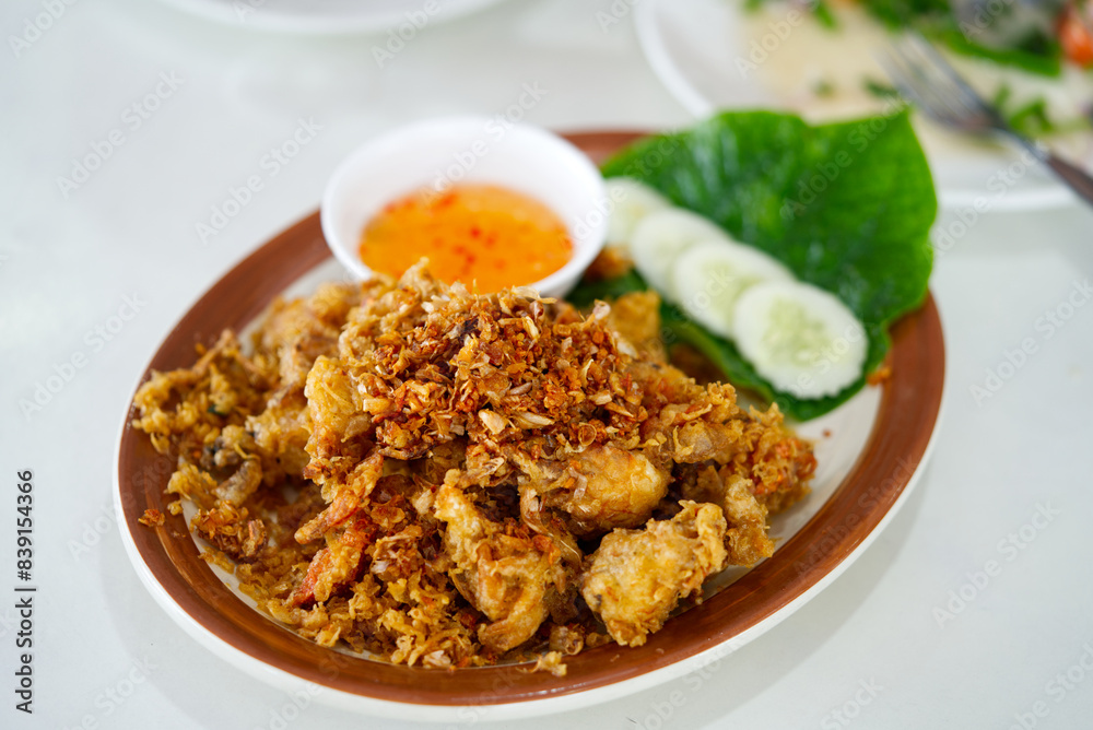 Thai food delicious menu, deep fried soft shell crab. Deep fried soft shell crabs with sweet sauce and silced cucumbers and green leaf vegetables on white table. Thai food delicious menu, deep fried soft shell crab. Deep fried soft shell crabs with sweet sauce and silced cucumbers and green leaf vegetables on white table.