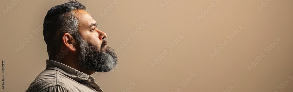 Fototapeta premium A man with a beard stares into the distance with a contemplative expression