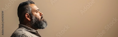 A man with a beard stares into the distance with a contemplative expression