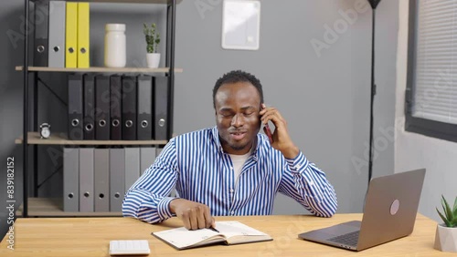 Black African American Man Using Smartphone at office. Happy Man Smiling speaking and chatting to colleagues and clients