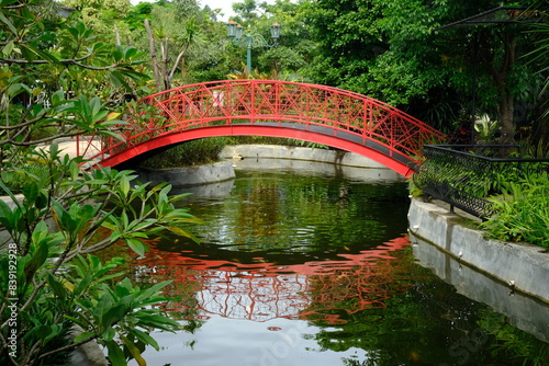 Konstfotografi curved red iron bridge in a tropical garden