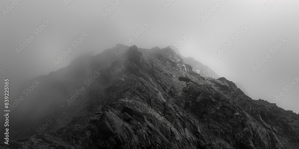 Mountain summit enveloped in fog, close-up on faint outlines of rocks, cool, subdued morning light. Mountain summit enveloped in fog, close-up on faint outlines of rocks, cool, subdued morning light.
