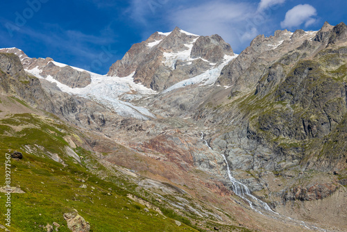 Tour du Montblanc beautiful mountain ladscapes of the Alps green valley, snow summit of Montblanc and rocky peaks of Aiguille du Midi in summer sunny weather blue sky, trekking and hiking in Chamonix photo