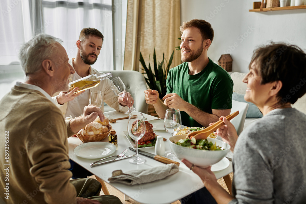 A gay couple shares a meal with parents at home. A gay couple shares a meal with parents at home.