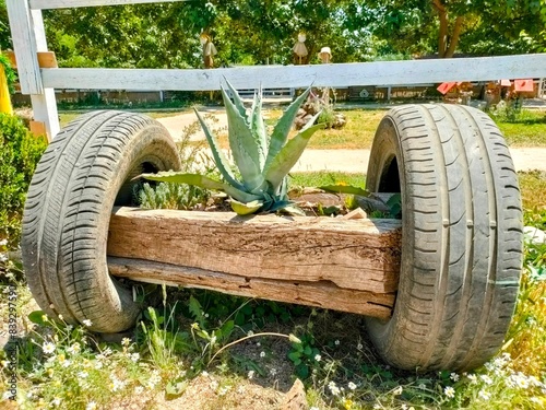 A decorative design made with car tires for a flower pot in the park on a sunny day.