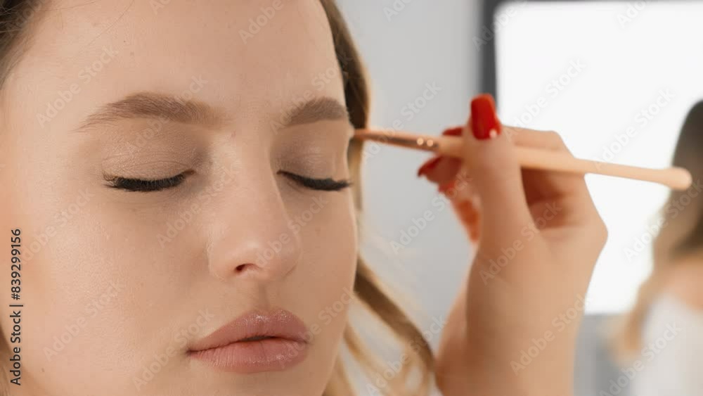 A skilled makeup artist meticulously applies eyeshadow to enhance a models eyelids, achieving a flawless look with fine detail. Closeup work and technique create a polished finish A skilled makeup artist meticulously applies eyeshadow to enhance a models eyelids, achieving a flawless look with fine detail. Closeup work and technique create a polished finish