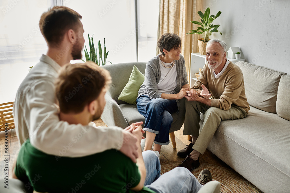 A gay couple sits close together while parents listen attentively. A gay couple sits close together while parents listen attentively.