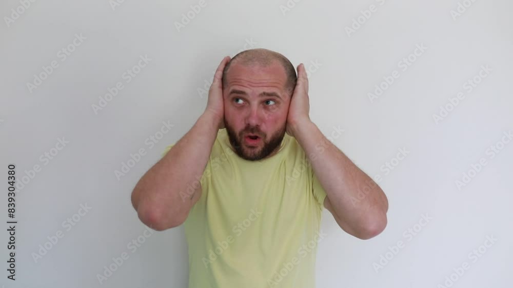 Adult Man in Yellow Shirt Expressing Frustration With Hands on Ears Indoors Adult Man in Yellow Shirt Expressing Frustration With Hands on Ears Indoors
