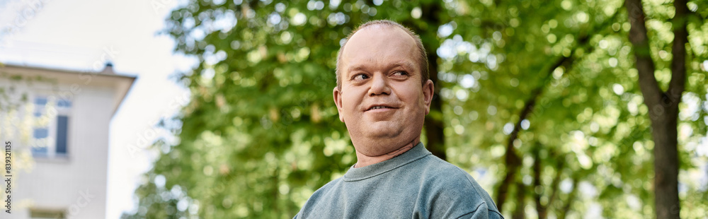 A man with inclusivity smiles warmly as he walks through a lush park on a bright summer day. A man with inclusivity smiles warmly as he walks through a lush park on a bright summer day.