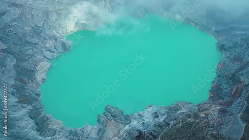 Panoramic drone view of turquoise sulfur water lake, surrounded by rock cliff at Kawah Ijen volcano. Aerial perspective in East Java, Indonesia. Natural landscape background