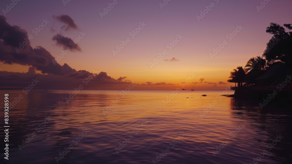 Fototapeta premium A picturesque sunrise over calm waters, with the first light of dawn painting the sky in soft hues of orange and purple