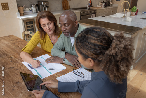 Financial advisor showing senior couple their investments using a digital tablet