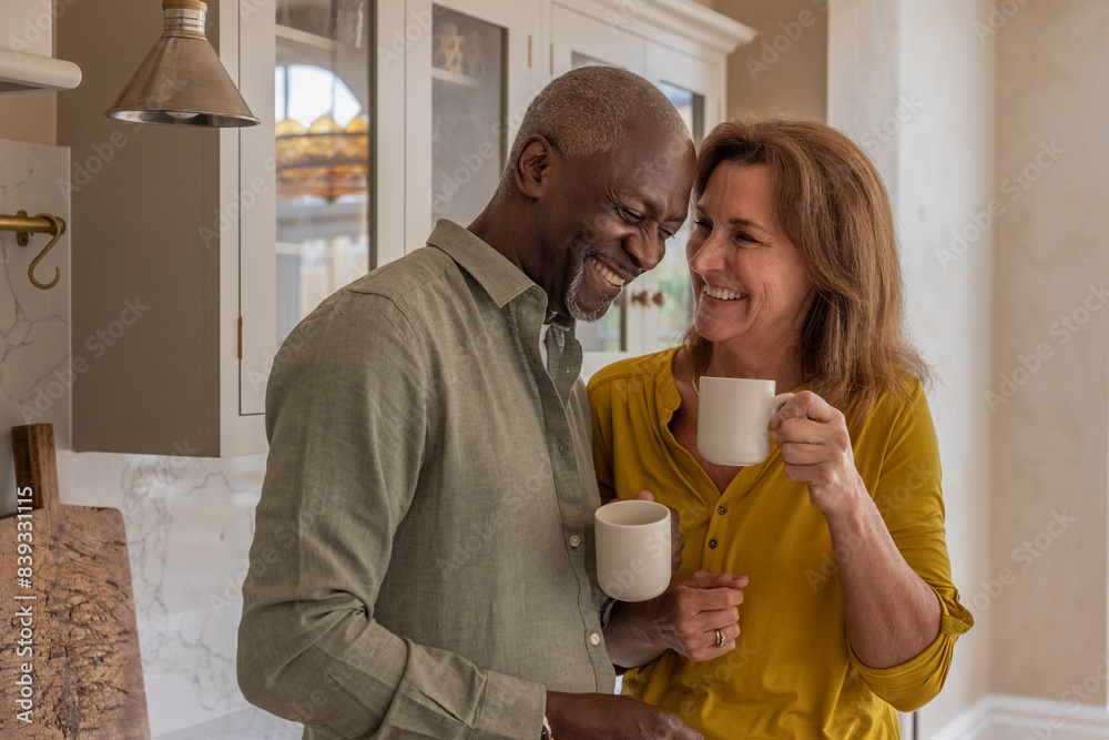 Senior carefree couple laughing together at home in the kitchen Senior carefree couple laughing together at home in the kitchen