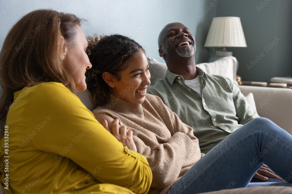 Senior couple with grown up daughter laughing together on a sofa at home Senior couple with grown up daughter laughing together on a sofa at home