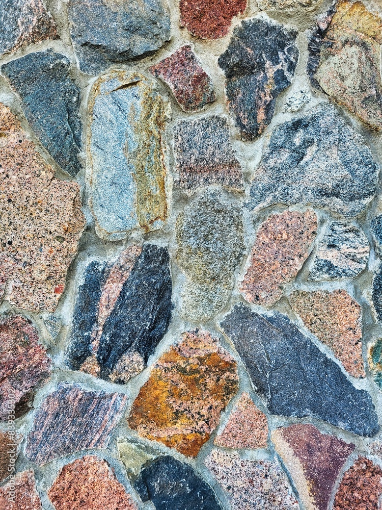 Fototapeta premium Decorative background. Stone wall background texture photo. Background texture of stone. Colorful small stones in the soil after rain. Old wall masonry, closeup. Old brick wall. Damaged stone wall