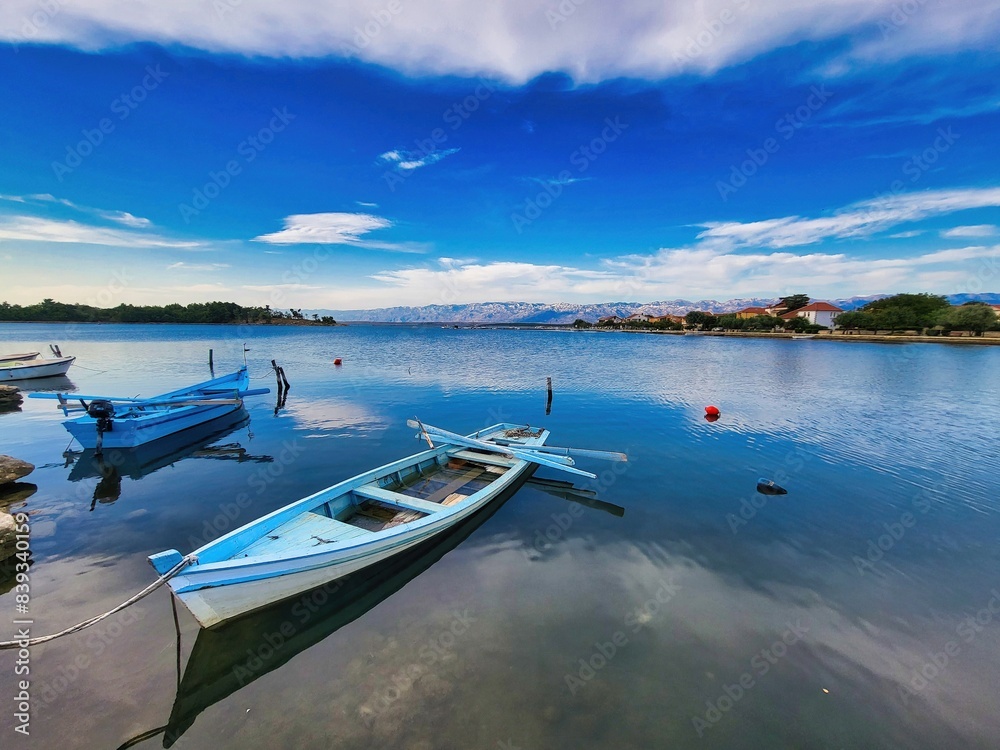 Fisherman boat floating in the beautiful sea and clear sky. Sea water spray around motorboat. From above you have a clear view of the beautiful coral reefs and soft, white sand. Drone shots Fisherman boat floating in the beautiful sea and clear sky. Sea water spray around motorboat. From above you have a clear view of the beautiful coral reefs and soft, white sand. Drone shots