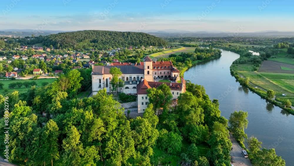 Tyniec near Krakow, Poland. Benedictine abbey, monastery, Baroque church with Gothic presbytery on the rocky cliff and its water reflection in Vistula River. Aerial 4K video. Summer, sunset light Tyniec near Krakow, Poland. Benedictine abbey, monastery, Baroque church with Gothic presbytery on the rocky cliff and its water reflection in Vistula River. Aerial 4K video. Summer, sunset light