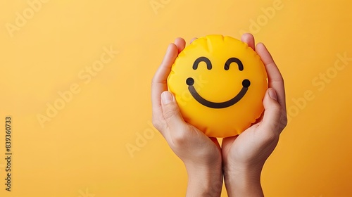 Hands Holding Smiling Face Emoji on Yellow Background