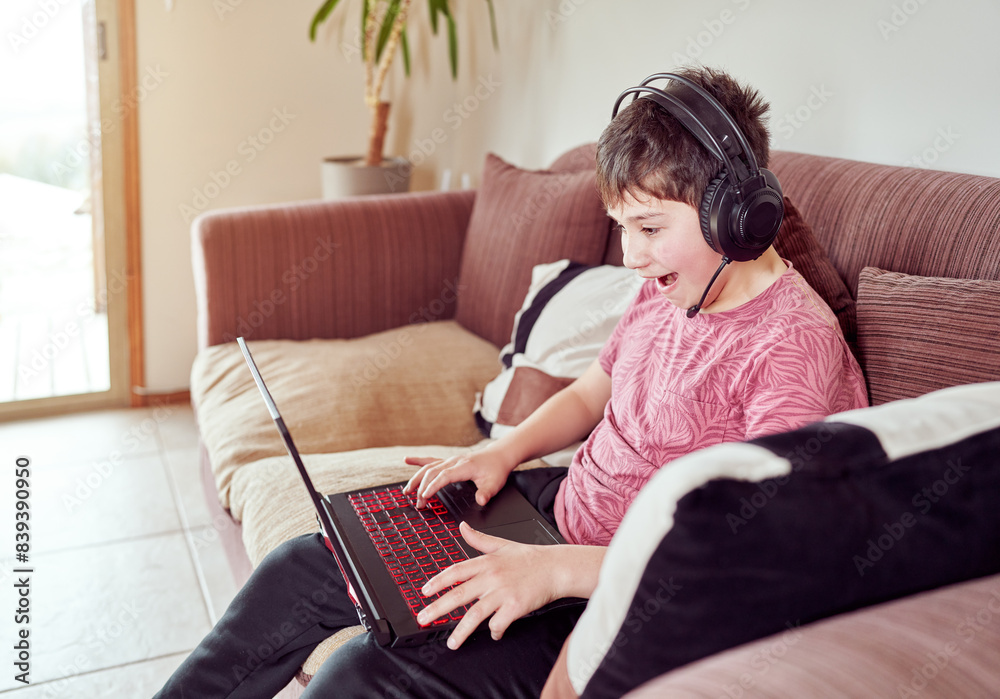 Fototapeta premium excited boy playing video games on his computer sitting in the living room of his home