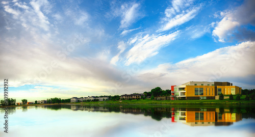 Sunrise Sioux Falls Landscape over the Lake Lorraine in South Dakota: Dramatic cloudscape and water reflections of the cottonwood trees and modern buildings  photo
