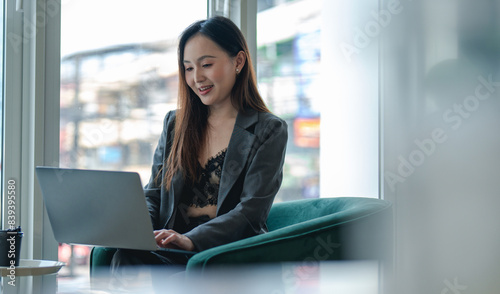 Smiling young asian businesswoman using computer at home office workplace  happy korean employee working on laptop  attractive japanese or chinese woman student studying communicating online with pc