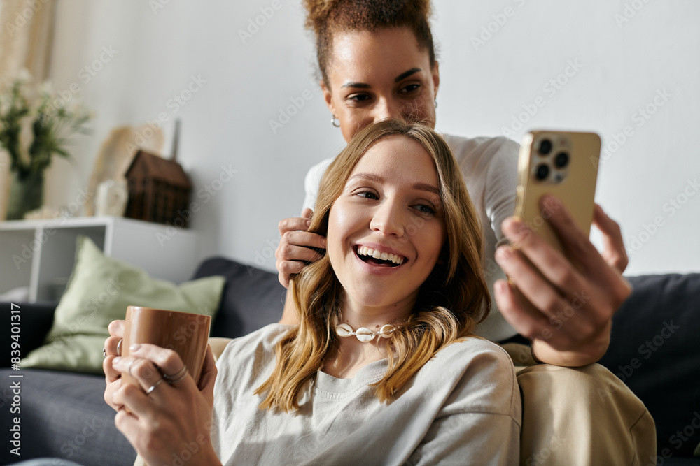 Fototapeta premium A diverse lesbian couple enjoys a relaxing afternoon at home, sharing a laugh and a warm beverage.