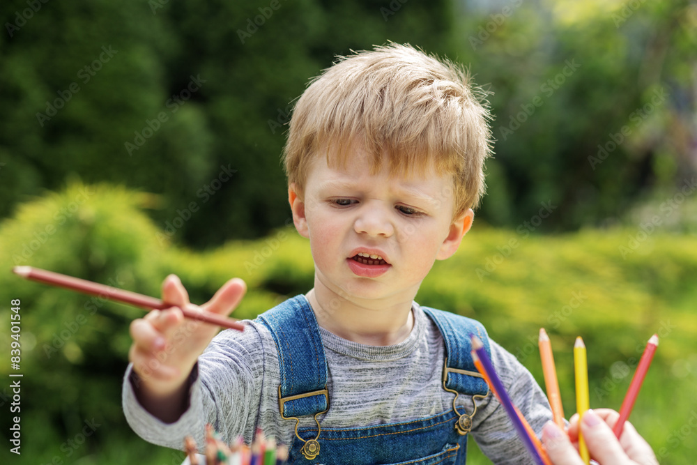 Kid boy choosing colored pencil in garden. Early years. Baby development. Kid boy choosing colored pencil in garden. Early years. Baby development.