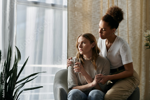 A lesbian couple sits together in their home, one comforting the other. photo