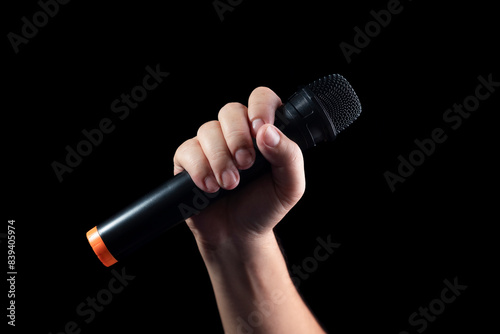 black microphone Male singer's hand holding microphone on modern singing stage On a black background and hands