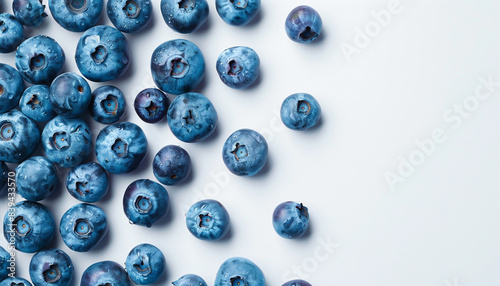 Fresh blueberries scattered across aa light, clean surface. The deep blue and purple hues of the berries stand out against the soft background, with some berries featuring natural speckles.