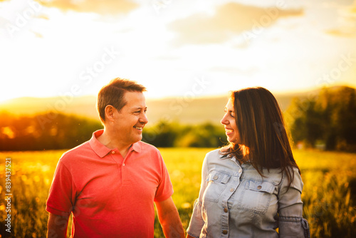 couple standing and hugging before a kiss against the background of the sunset in the field
