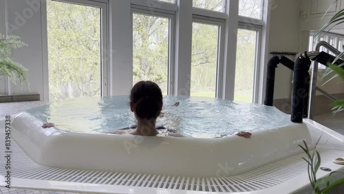 Young Woman in a Jacuzzi at a SPA hotel. Water massage. Female girl enjoys her holiday at a spa resort. View from the back.