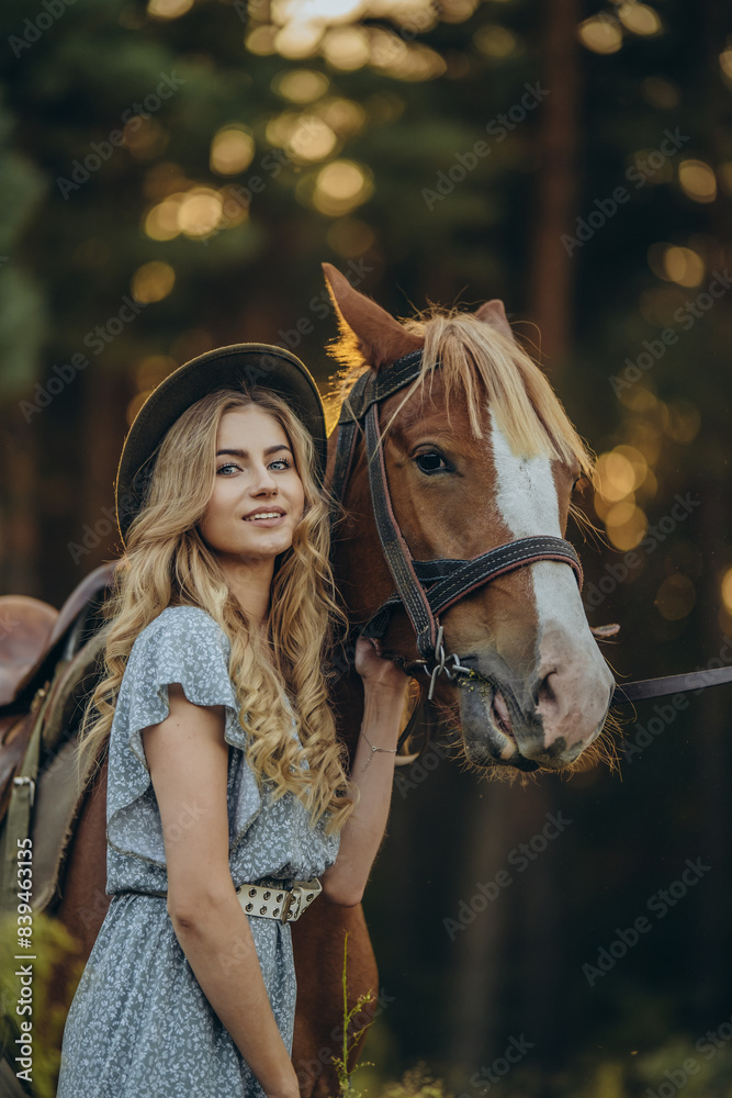 Obraz premium A young beautiful woman walks with her horse in the forest in early autumn. Walking with a horse in the forest.