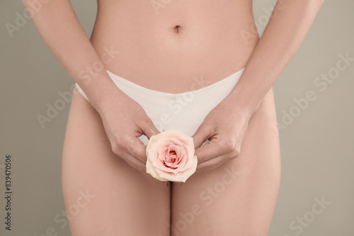 Gynecology. Woman in underwear with rose flower on grey background  closeup