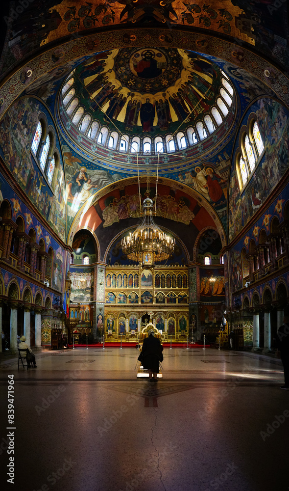 Obraz premium Old woman prays on her knees in the middle of Holy Trinity Orthodox Cathedral of Sibiu, Transylvania, Romania