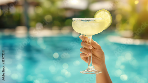 margarita cocktail in hands against the backdrop of the pool, summer vacation in tropical luxury hotels, delicious alcohol drink margarita glass