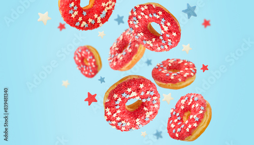 Flying or levitating donuts decorated for 4th of July with colors of American flag and small stars clipping path on blue background for party. Happy 4th of July. Labor, Independence or Presidents Day.