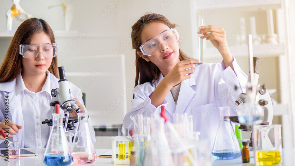 Attractive scientist woman testing chemical sample in flask at laboratory with lab glassware background. Science or chemistry research and development concept. Attractive scientist woman testing chemical sample in flask at laboratory with lab glassware background. Science or chemistry research and development concept.