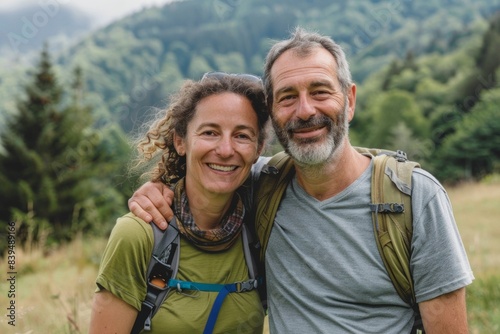 Portrait of a smiling caucasian couple in their 40s sporting a breathable hiking shirt on quiet countryside landscape