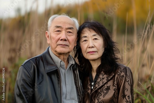 Portrait of a tender asian couple in their 60s sporting a stylish leather blazer while standing against quiet countryside landscape