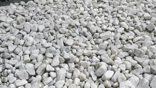 White marble carrara pebbles full fram in zen rockery, camera panning left