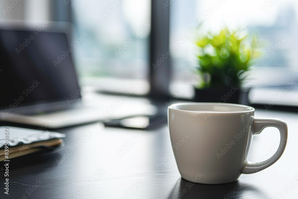 A white coffee cup sits on a table next to a laptop and a notebook A white coffee cup sits on a table next to a laptop and a notebook