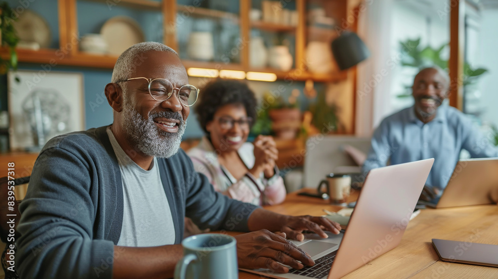 Mature colleagues engaging in a cheerful discussion while using laptops, showcasing their expertise and the integration of technology in a friendly office atmosphere.